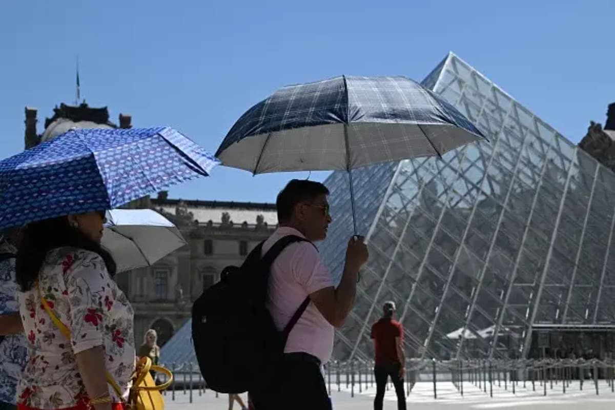 Visitantes usam guarda-chuvas para se proteger do sol durante as altas temperaturas no Museu do Louvre, em Paris, França - Foto: Benjamin Girette/Bloomberg