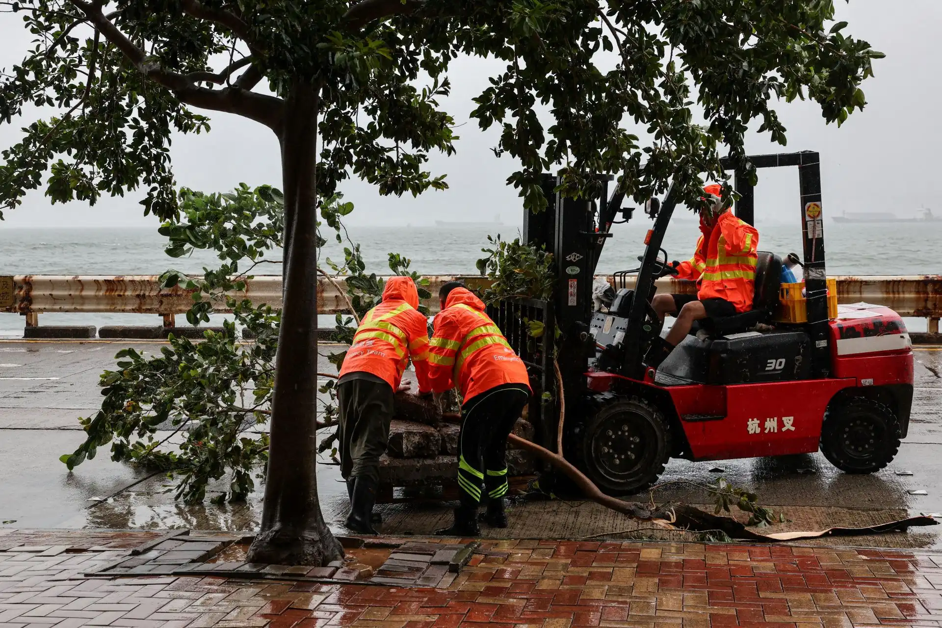 Trabalhadores removem detritos e obstáculos caídos na estrada após a passagem do Tufão Noul, em Hong Kong, China - (Foto: Tyrone Siu)