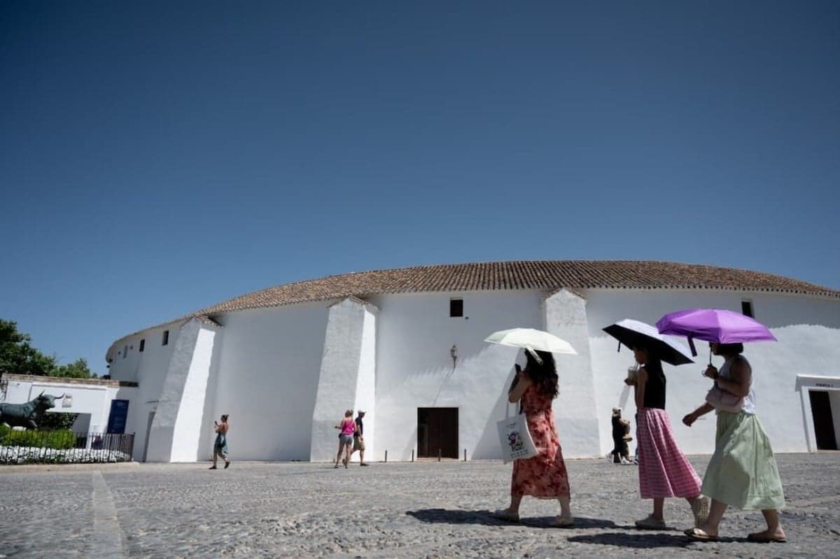 Turistas se protegem do sol com guarda-chuvas enquanto visitam a praça de touros em Ronda, no sul da Espanha, durante a primeira onda de calor do verão - Foto: Jorge Guerrero / AFP