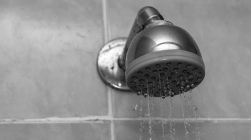 cabeça de chuveiro (ducha) de metal com água em banho