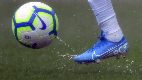 chuteira de futebol chutando uma bola de futebol em um campo